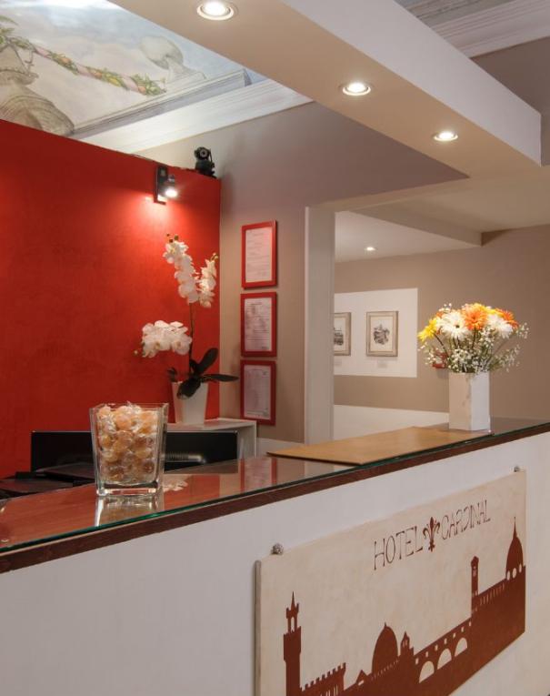Reception dell'Hotel Cardinal con decorazioni floreali e opere d'arte.