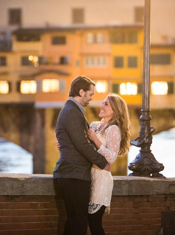 Coppia felice abbracciata davanti a un ponte illuminato.